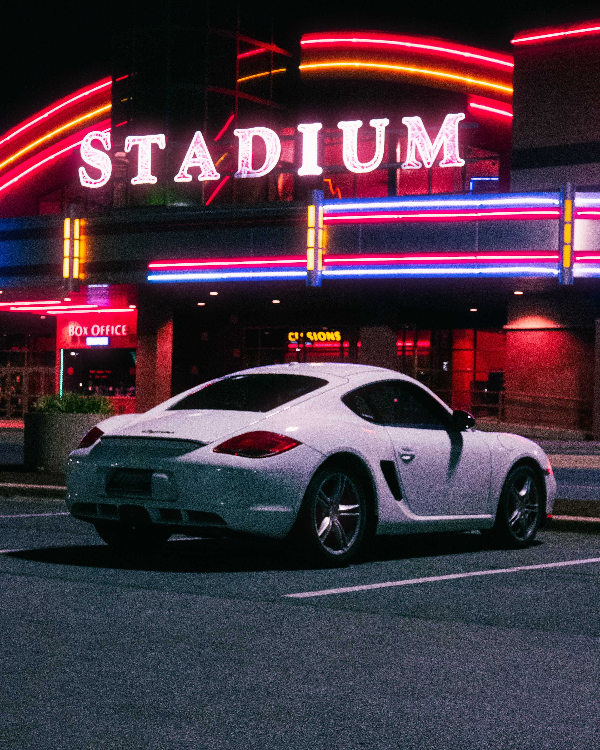 white coupe in front of neon-lit theater